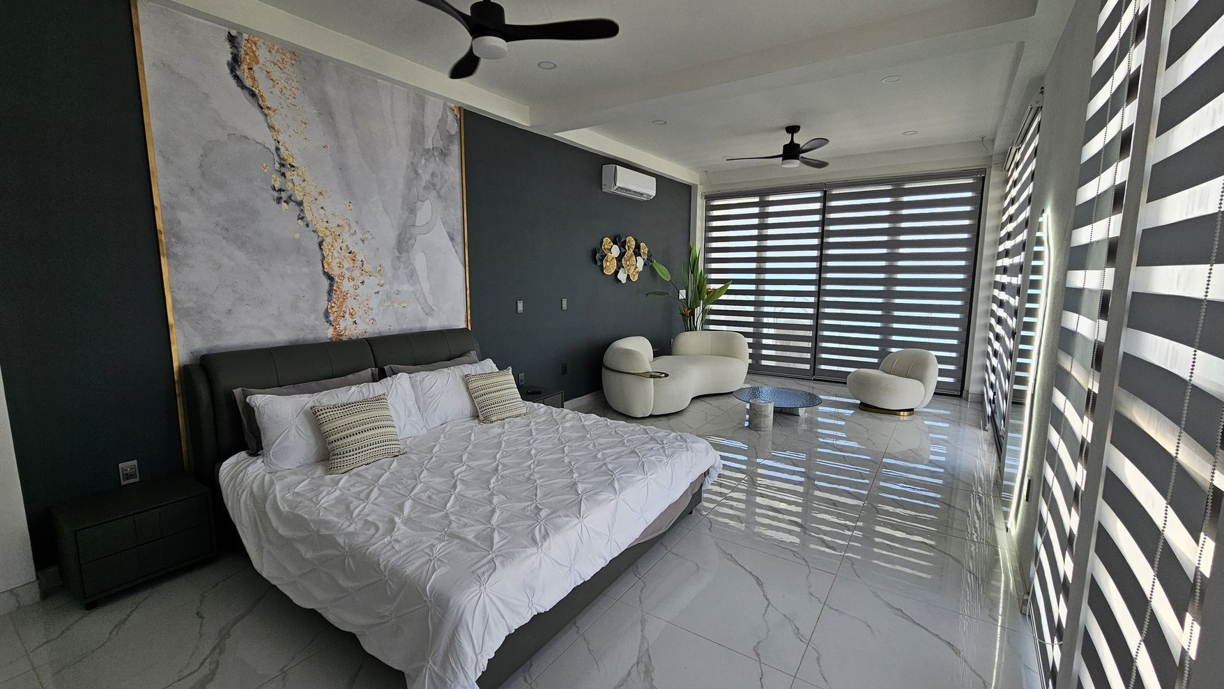 Bedroom suite with a lounge area, dark feature wall and light furnishings